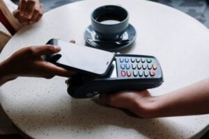 woman paying with mobile phone in cafe - salary package Belgium